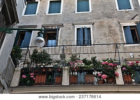 Part Of An Old Gray Venetian House With Cozy Floral Balconies.