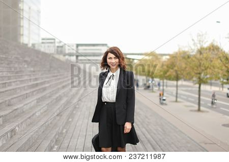 Caucasian Female Manager Standing On Stairs Outside In High Buildings Background. Concept Of Profess