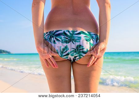 Woman In Bikini Stands On White Sand Beach In Front Of Turquoise Blue Sea. Woman In Bikini On Sunny 