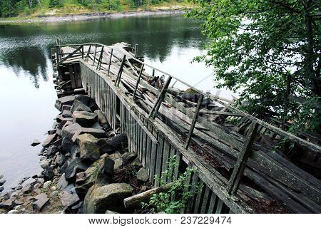An Abandoned Pier Near The Skete Of All Saints. Aged Photo. Summertime. Deserted Old Wooden Dock. To