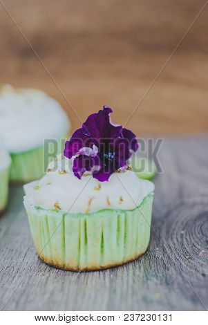 Cupcake Decorated With Meringue And Violet Flower And Lime Peel, Selective Focus