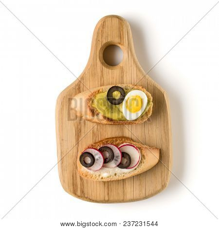 Open faced sandwich canape or crostini on a wooden serving board isolated on white background closeup. Top view. Vegetarian tartarine.