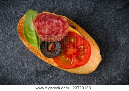 Open faced sandwich canape or crostini on dark stone background closeup. Top view.