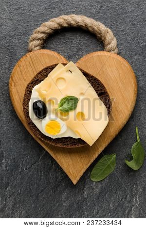 Open  faced cheese sandwich canape or crostini on a wooden serving board  on dark stone background closeup. Top view.