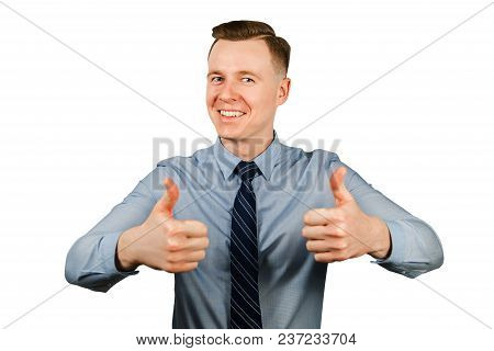 Young Businessman Dressed In Blue Shirt And Tie Shows Thumbs Up And Smiles, Isolated On White Backgr