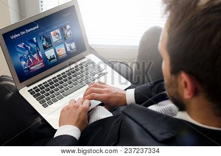 Man Using Laptop For Watching Movie On Vod Service. Video On Demand Television Internet Stream Multi