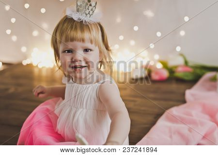 One Year Old Girl In A Festive Dress And The Crown.