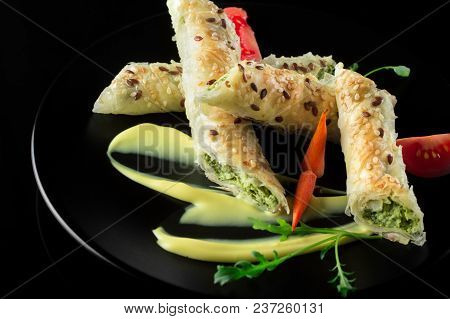 Puff Pastry With Spinach And Cheese Filling On A Black Plate And Black Background.