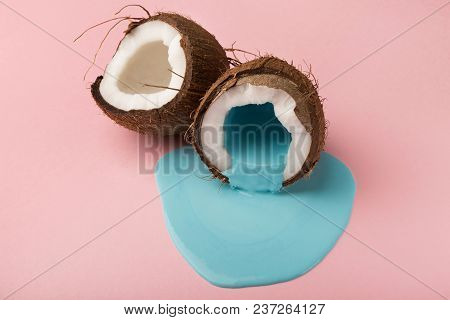 Blue Paint Flowing From Coconut Half On Pink Table. Creative Background With Copy Space, Bold Design