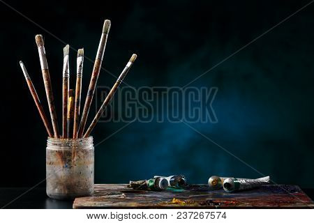 Paint brushes with a palette on a colored background.