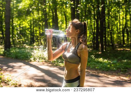 Young Woman Drinking Water After Running Outdoors.
