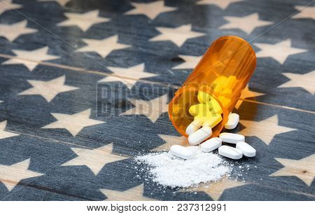 Front View Of Prescription Bottle Filled With Generic Opioid Pain Killer Tablets On Rustic Usa Flag 