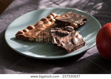 Dark And Milk Chocolate With Nuts And Apple On A Plate On The Table