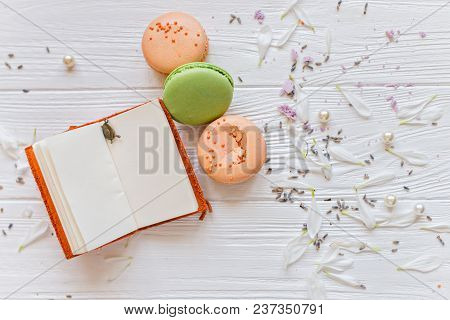 A Flat Lay Of A Colorful Macarons , Notebook For Records On The White Texture Background