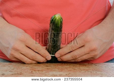Closeup Man's Hands Put On Condom On Cucumber.