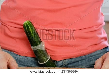 Closeup Man's Hands Put On Condom On Cucumber. A Torn Condom.