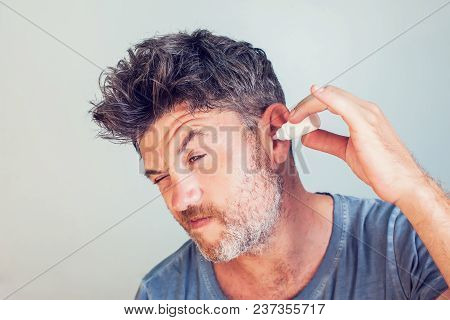 Man Using Ear Drops On Gray Background