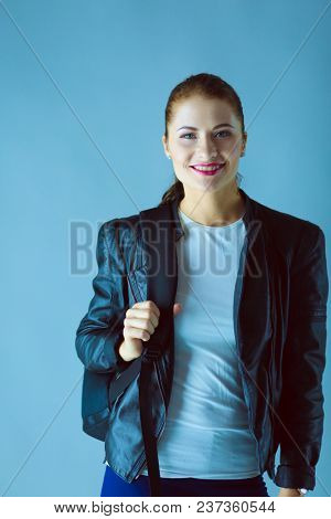 portrait of beautiful young brunette woman in stylish black jacket on gray.