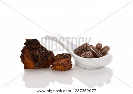 Inonotus Obliquus, Chaga Pieces And Gel Capsules On Spoon Isolated On White Background. Medicinal Mu