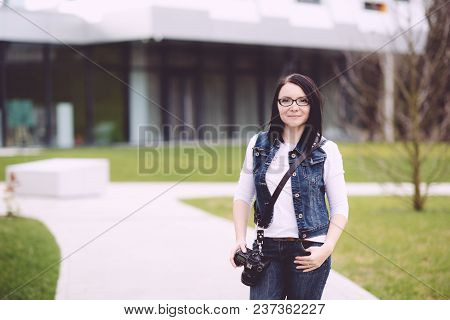 A Professional Photographer Performs His Work. Attractive Young Woman Talking Pictures Outdoors