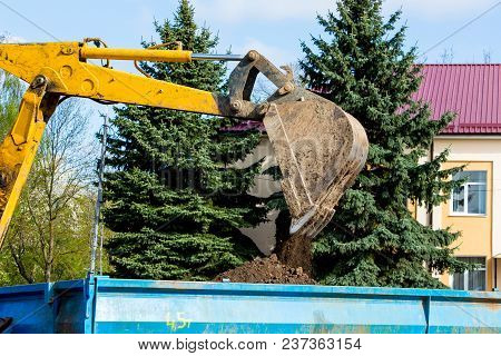 Excavator Bucket  Pours  Earth Onto Tractor Traileris