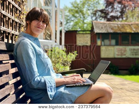 Beautiful brunette woman working on a laptop in the garden