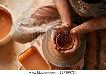 Close-up Hands Of A Male Potter In Plaid Shirt And Dirty Apron Who Molds A Vase From Clay, Selective