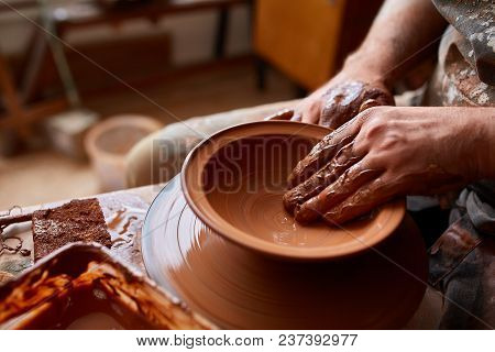 Close-up Hands Of A Male Potter In Plaid Shirt And Dirty Apron Who Molds A Vase From Clay, Selective