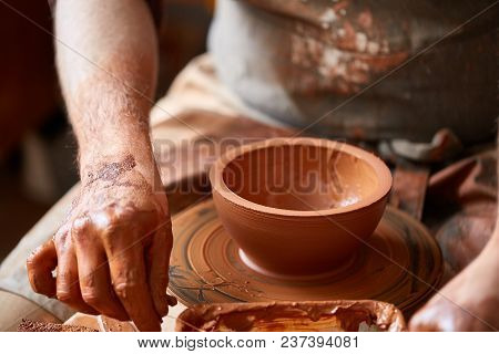 Close-up Hands Of A Male Potter In Plaid Shirt And Dirty Apron Who Molds A Vase From Clay, Selective
