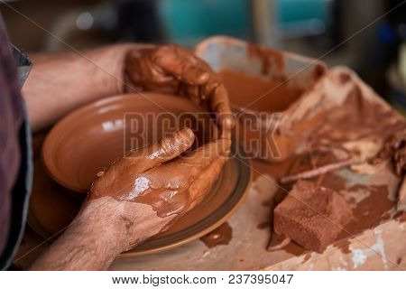 Close-up Hands Of A Male Potter In Plaid Shirt And Dirty Apron Who Molds A Vase From Clay, Selective