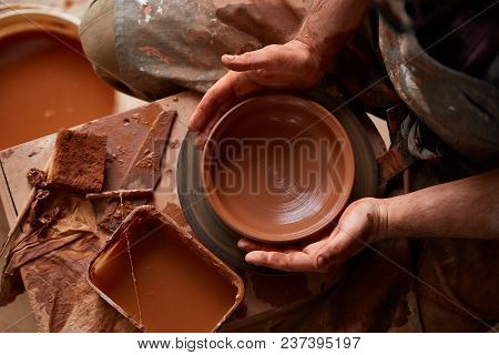 Close-up Hands Of A Male Potter In Plaid Shirt And Dirty Apron Who Molds A Vase From Clay, Selective