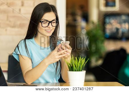 Beautiful Student Girl Using Smartphone For Text Messages In Modern Stylish Coworking Office
