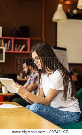 Brunette Girl Working With Tablet Computer Sitting In Coworking Cafe Office