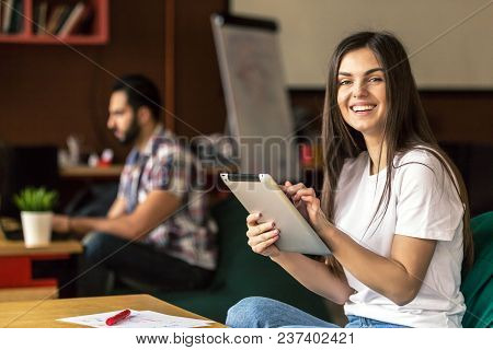 Portrait Of Smiling Attractive Brunette Girl Enterpreneur Work With Tablet In Modern Office, Sitting