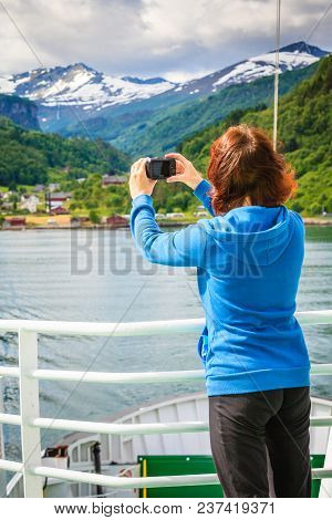 Tourism Vacation And Travel. Tourist Woman On Cruise Ship Enjoying Fjord View, Taking Photo With Cam