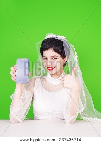 Caucasian Fiancee Holding A Mobile Phone And Pointing At It. Young Fiancee With A Mobile Phone. Fian