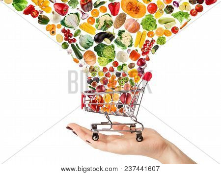 Female Hand Holding Grocery Cart With Vegetables And Fruits Falling In It Isolated On White. Healthy