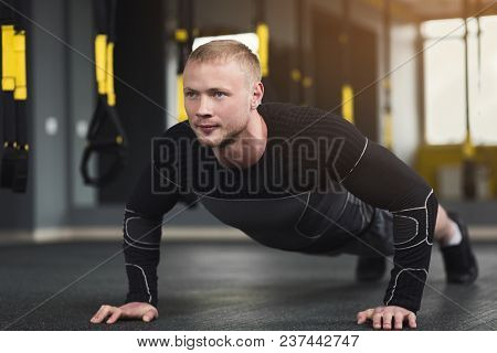Young Man Workout In Fitness Club. Closeup Portrait Of Caucasian Guy Making Plank Or Push Ups Exerci