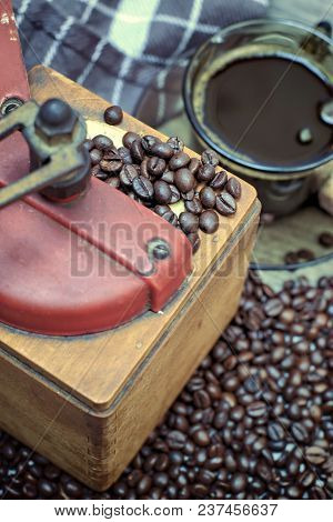 Old Coffee Grinder With A Cup Of Coffee, Coffee Beans On A Wooden Background.