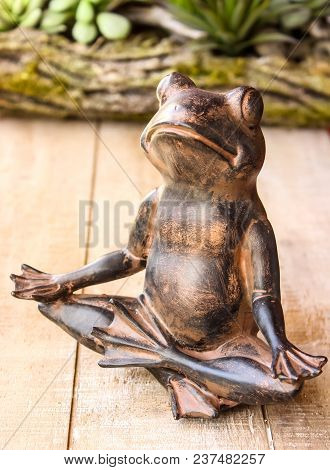 Yoga Frog Meditating In Lotus Pose. Body, Mind And Soul Balance Concept. On Wooden Background