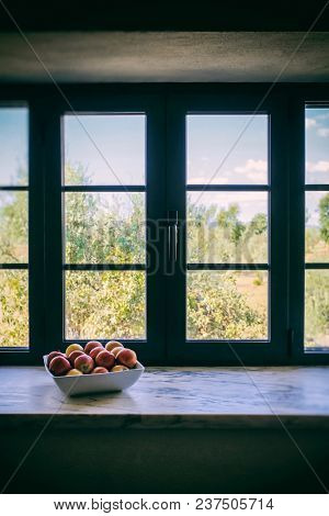 A bowl with assorted fruits near a large window with natural light