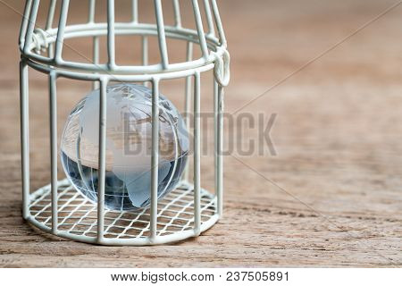 Glass Globe With America Map Inside Birdcage On Wooden Table Metaphor Of Limited Thinking, Underprot