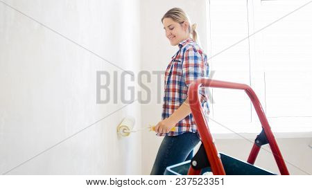 Portrait Of Beautiful Blonde Woman Painting Walls In Hwite Color