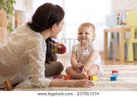 Nanny Or Babysitter Looks After Kid Toddler. Baby Girl Playing With Educational Toys In Nursery. Chi