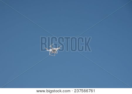 White Quadrupter With Propellers Flies In The Blue Sky And Photographs Landscapes