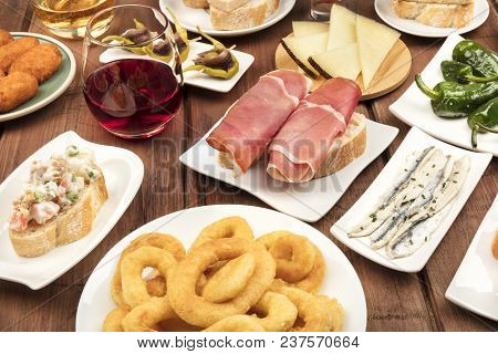 The Food Of Spain. A Photo Of Many Different Spanish Tapas On A Dark Rustic Texture. Jamon, Cheese, 