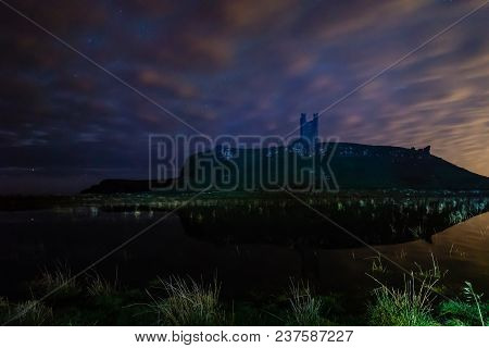 Dunstanburgh Castle At Night, Reflected In Floodwater After Heavy Rain In Northumberland