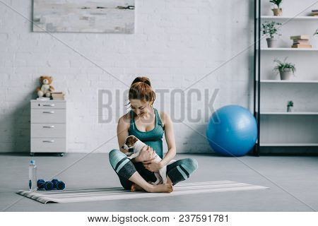 Beautiful Pregnant Woman Sitting On Yoga Mat With Jack Russell Terrier Puppy