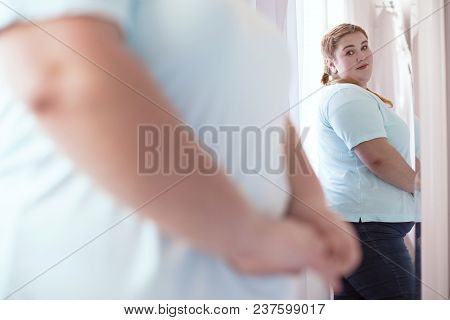 Mirror Lies. Nice Young Woman Looking Disappointed While Evaluating Her Figure In The Mirror