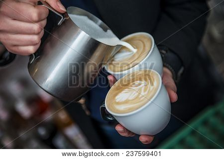 Barista Making 2 Cups Of Cappuccino At Once Pouring Milk Into Coffee